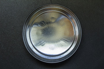 Lid or base of food tin can on black background
