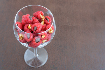 Red raspberries treats with walnuts, and chocolate chips in a wine glass
