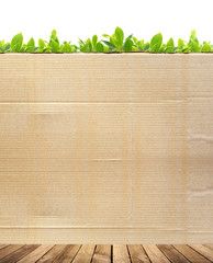 Wooden floor and cardboard wall on green leaves background
