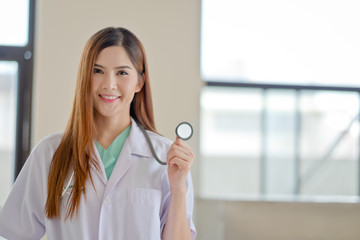 Happy smiling young beautiful female doctor showing blank area for sign or copyspace