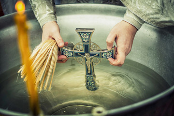 baptism, Orthodox feast, the Christian feast of the baptism, the cross in Holy water, Holy water in a tub with a cross and the hands of the priest