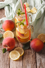 Fruit lemonade with peaches, ice and mint in a glass jar closeup. vertical
