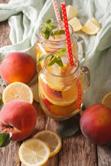Refreshing drink with lemon, peach, ice and mint in a glass jar. vertical
