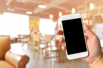 Woman hand holding smartphone against blur bokeh of coffee shop
