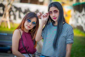 Two teenage girls friends in hipster outfit.at the park outdoors make selfie on a phone And fashion sunglasses.