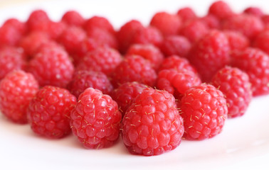 Fresh raspberries in heart shape on bright background