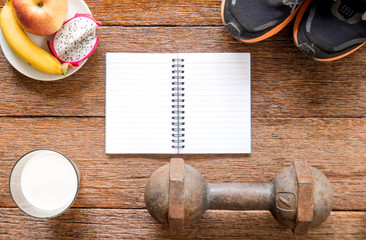 Iron dumbbell,Sports shoes and notebook with milk and fruit (ban