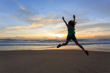 woman traveller happy jumping on the beach with sunrise