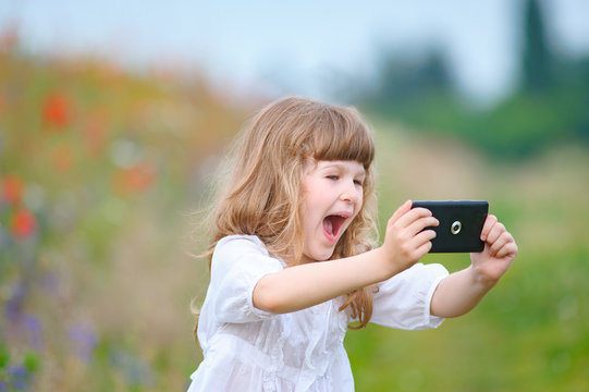 little girl makes selfie in nature 