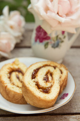 Biscuit roll with jam on old wooden background. Selective focus