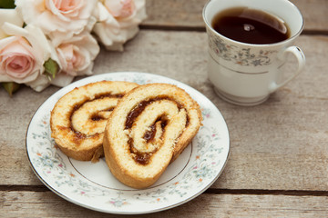 Biscuit roll with jam on old wooden background. Selective focus