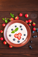 Healthy yogurt with strawberry and blueberyy on wooden background. Rustic food. Flat lay, top view