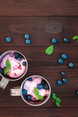 ice cream and blueberry in a cups on wooden background, top view
