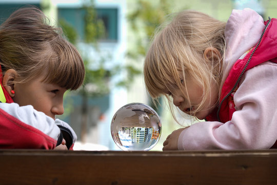 Children look at a transparent ball. The bowl is reflected beautiful new building. The concept - dream of an apartment housing.