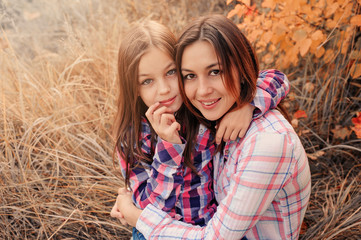 happy mother and daughter on cozy walk on sunny field