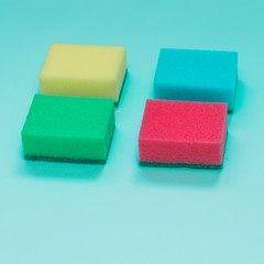 four sponges in different colors on blue background.