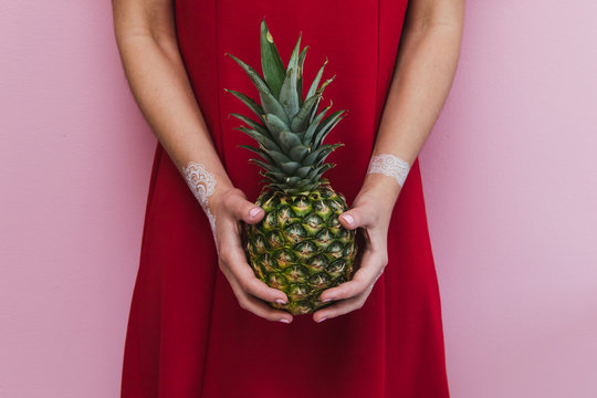 Pineapple in lady's hands. Trendy and stylish fashion.