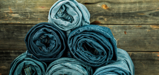 bunch of jeans twisted on a wooden background, fashionable clothes