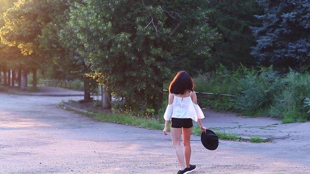 Cute female Young beautiful Asian girl in the green park sun background portrait, look to camera and shows emotions happy and rejoices walking doing to camera and spinning