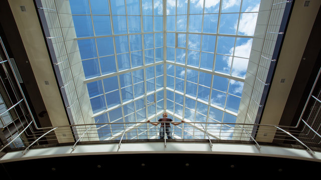 The man stands on the bridge in the business center. Wide angle view