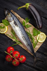 Mackerels served on parchment with lemon, tomatoes, eggplant, and herbs