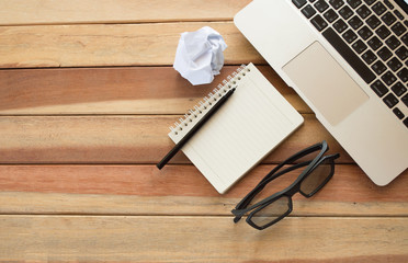 Office wood table with notepad, computer and flower.On top view.