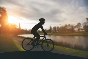 Fototapeta na wymiar Silhouette of a man on muontain bike on public park at sunset.