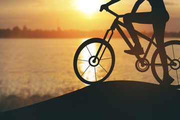Fototapeta premium Silhouette of a woman on muontain bike, sunset.Vintage color