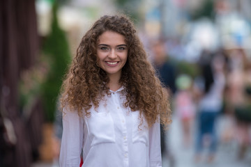 Obraz premium The beautiful curly woman on the background of people