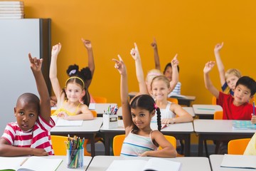 Fototapeta School kids raising hand in classroom obraz