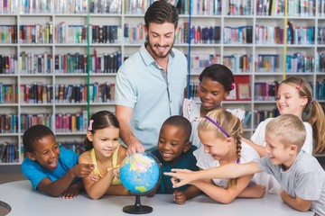 Pupils and teacher looking at globe in library 