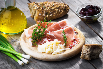 Thin slices of prosciutto with  pecorino on wooden background
