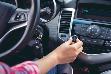 Car dashboard. Radio closeup. Woman sets up radio