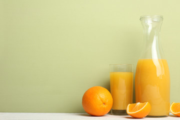 a glass bottle of orange juice on a white wooden background