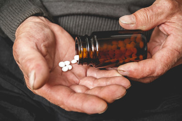 Many pills from a glass bottle in the Senior hands. Painful old age. Caring for the health of the elderly