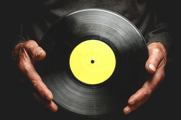 Vintage vinyl record in the hands of an elderly man.