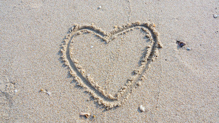 Draw the heart on the sand beach.