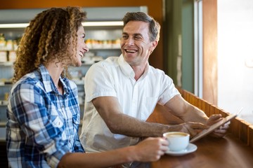 Happy couple using digital tablet in café