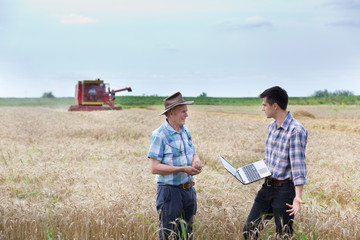 Farmers on field with combine harbester