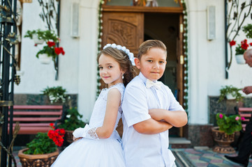 First holy communion, brother and sister stay at white dress bac