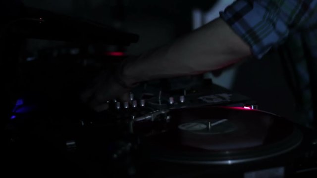 DJ scratching vinyl records and mixing on the Decks at a disco in Nightclub