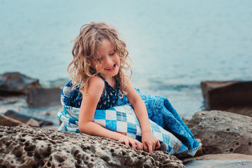 child girl relaxing on the stone beach on summer vacations
