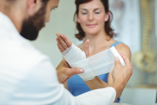 Physiotherapist Putting Bandage On Injured Hand Of Patient