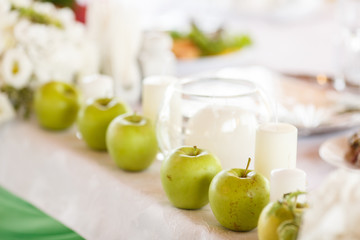 Green apples and white candles as an element of dinner table dec