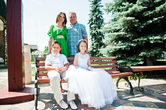 Happy family at first holy communion sitting on bench background