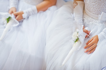 Hands with candles of little girls on first holy communion