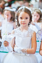 Portrait of cute little girl on white dress and wreath on first