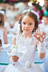 Portrait of cute little girl on white dress and wreath on first