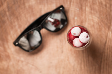 frozen cherries in the glasses and sunglasses on a wooden table