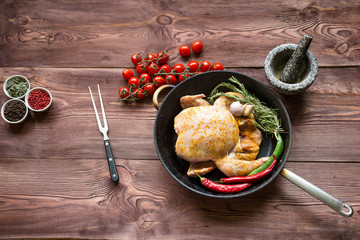 Whole roasted chicken with vegetables in cast-iron pan